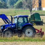 two tractors mowing and baling